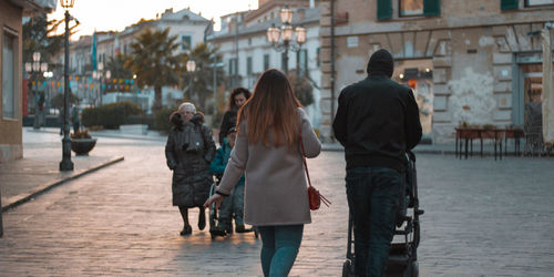 Rear view of people walking on street in city