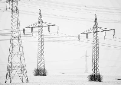 Low angle view of electricity pylon on field