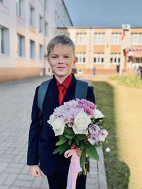 Portrait of boy with flower against building