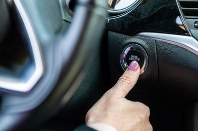 Woman starts the car engine with start-stop button. modern car interior, closeup