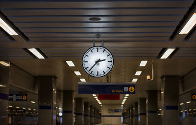 Low angle view of clock hanging from illuminated ceiling at railroad station