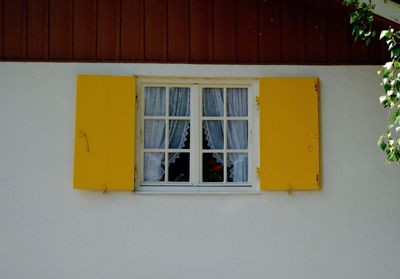 Low angle view of yellow window on wall of building
