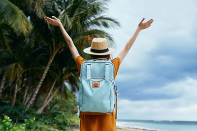 Rear view of woman standing by sea against sky