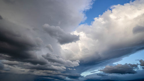 Low angle view of sunlight streaming through clouds