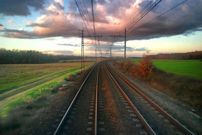 Railroad tracks against cloudy sky