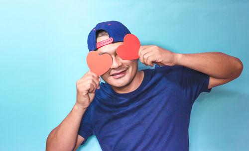 Portrait of young man holding blue against white background