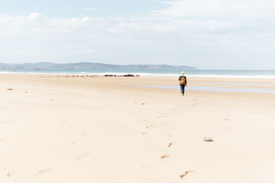 Rear view of person on beach against sky