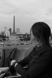 Portrait of woman looking at city buildings against sky