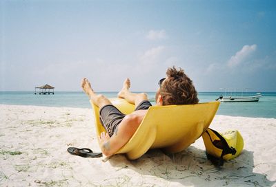 Rear view of young man relaxing on beach