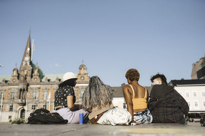 Surface level view of multiracial friends sitting in city on sunny day