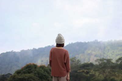 Rear view of woman standing against mountains and sky