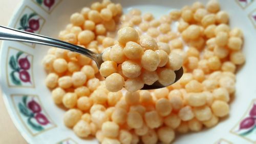 Close-up of wet cereal in spoon over bowl on table