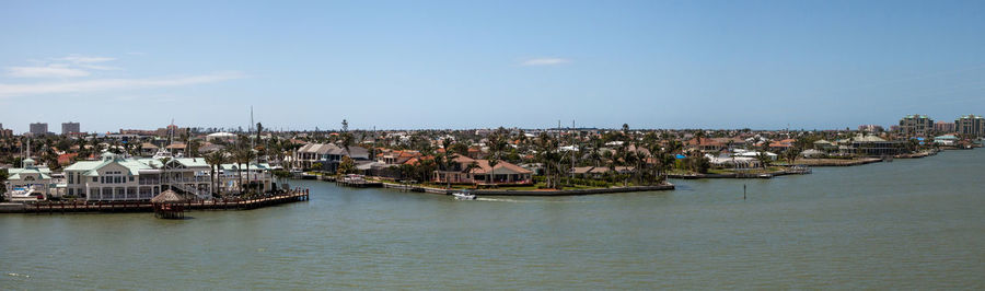 Sailboats in city by sea against sky