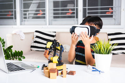 Young woman using mobile phone while sitting on table