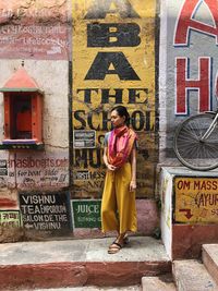 Full length of woman standing against graffiti wall