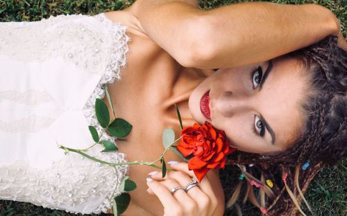 Close-up portrait of smiling woman with red flower