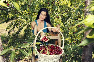 Portrait of young woman with fruits in basket