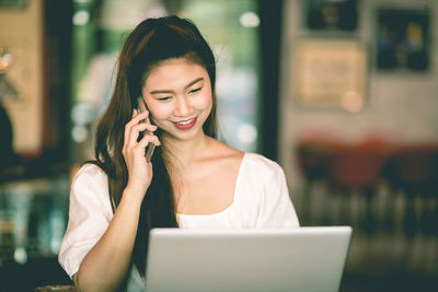 Smiling woman talking on mobile phone at cafe