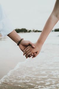 Midsection of couple holding hands in water
