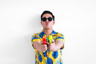 Portrait of young woman wearing sunglasses while standing against white background