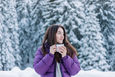 Woman drinking hot tea while on a road trip during winter.