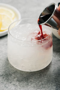 Pouring creme de cassis into a bramble cocktail