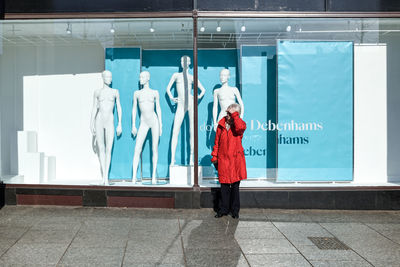 Full length of woman standing against red wall