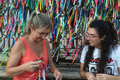 Portrait of two women placing colored ribbons on the church grid. 