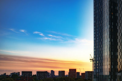 Buildings in city against sky during sunset