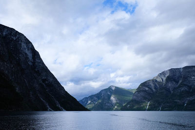 Scenic view of lake and mountains against cloudy sky