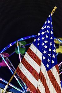 Low angle view of illuminated flags against clear sky at night during carnival. 