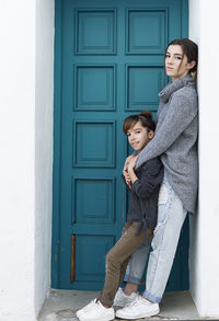 Portrait of siblings standing by door