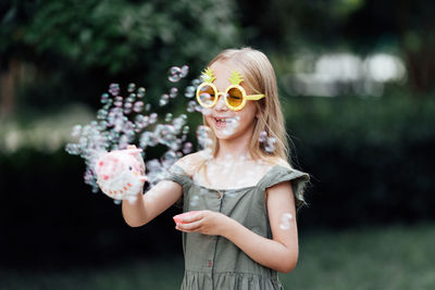 Portrait of young woman wearing sunglasses while standing against trees