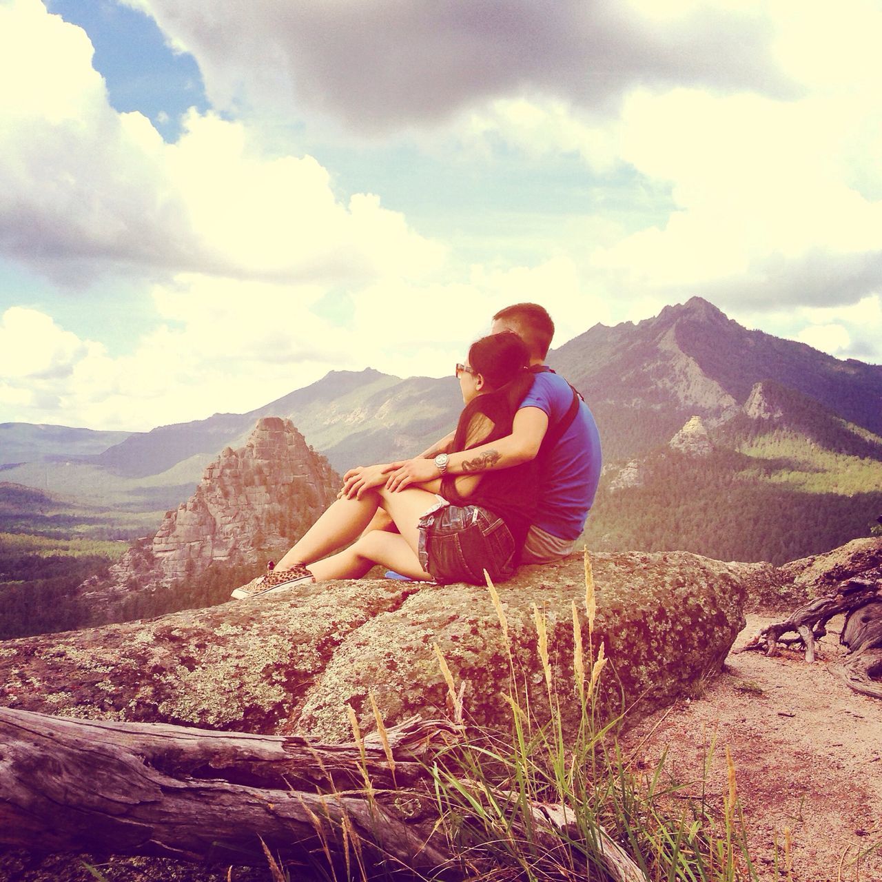 lifestyles, leisure activity, mountain, sky, casual clothing, full length, cloud - sky, landscape, togetherness, mountain range, rear view, beauty in nature, scenics, nature, tranquil scene, sitting, vacations