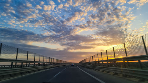 Bridge over road against sky during sunset