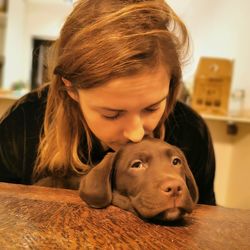 Close-up of woman with dog sitting at home