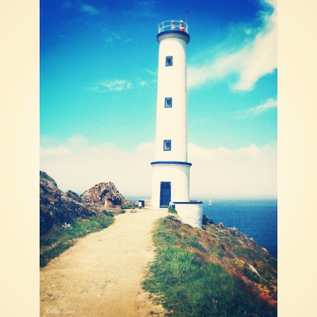 lighthouse, guidance, architecture, built structure, sky, building exterior, direction, protection, tower, sea, cloud - sky, cloud, safety, tranquility, mountain, day, tranquil scene, blue, nature, security