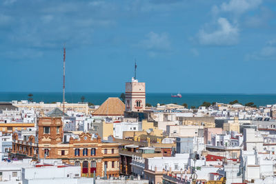 Buildings by sea against sky