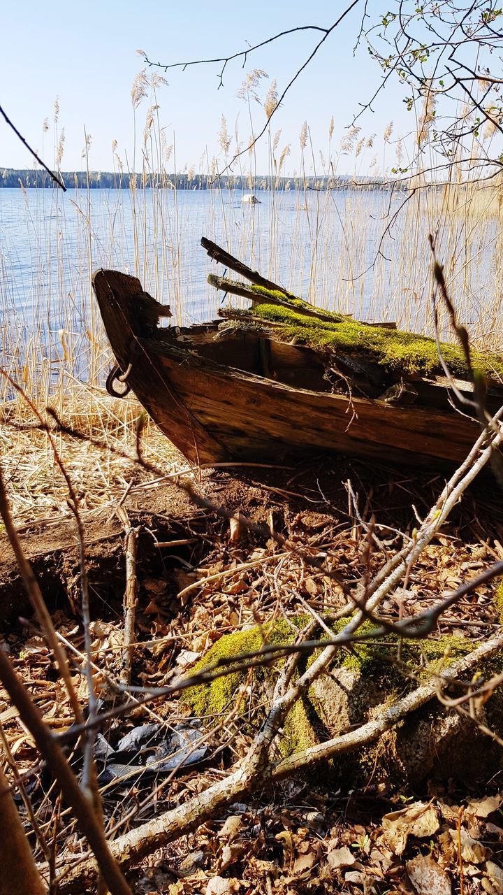 ABANDONED BOATS MOORED ON BEACH AGAINST SKY