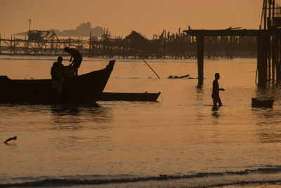 Silhouette fishermen in sea during sunset