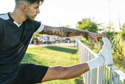 Boy warming up for sports boy supports his leg on a railing to do str