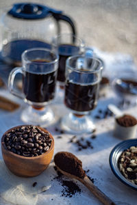 Still life with glass mugs of black hot coffee, coffee beans, coffee pot, coffee at home