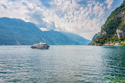 Sailboat sailing on sea by mountains against sky