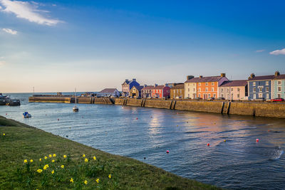 Bridge over river by buildings in city against sky