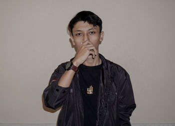 Portrait of young man standing against wall