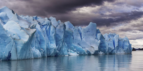 Scenic view of glacier by sea against sky