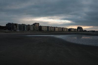 View of beach and buildings against sky during sunset