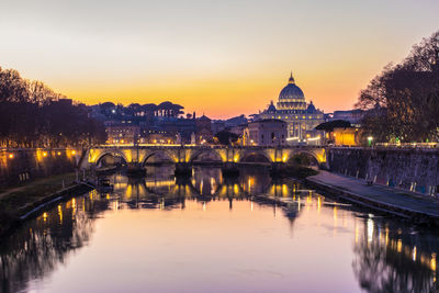 Illuminated bridge over river during sunset