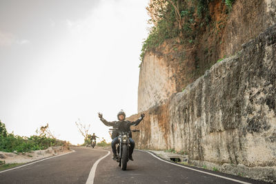 Rear view of man riding motorcycle on road