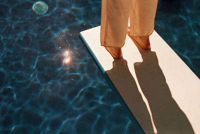 Low section of person standing on swimming pool